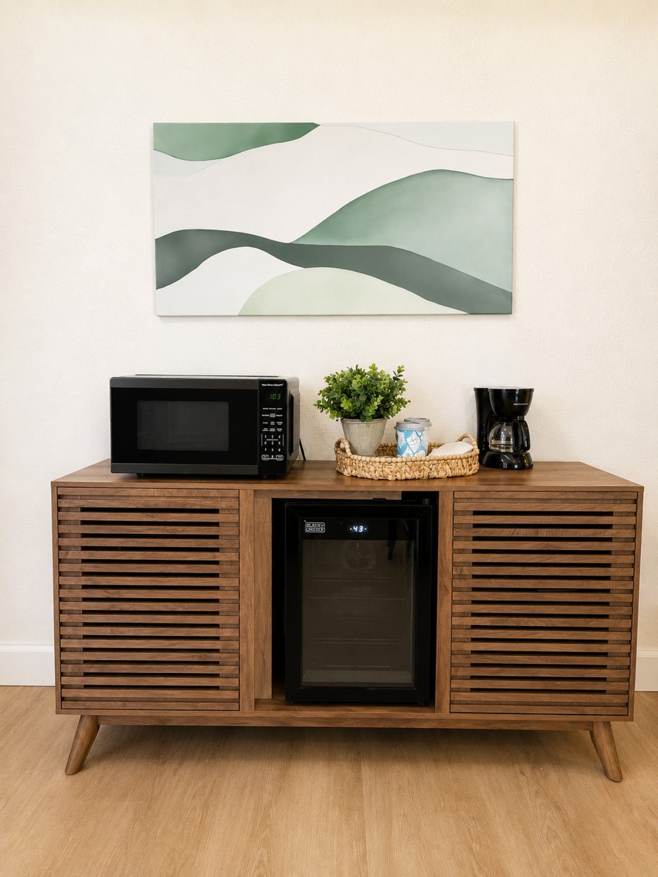 Ein Holzkabinet mit einer Mikrowelle, einer Kaffeemaschine und einem kleinen Kühlschrank.