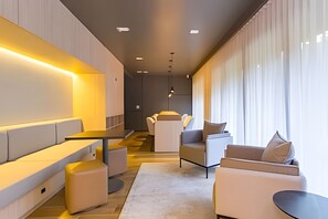 Ein modernes Wohnzimmer mit einer Couch, Sesseln und einem Couchtisch. Eine Treppe führt zu einer weiteren Ebene.