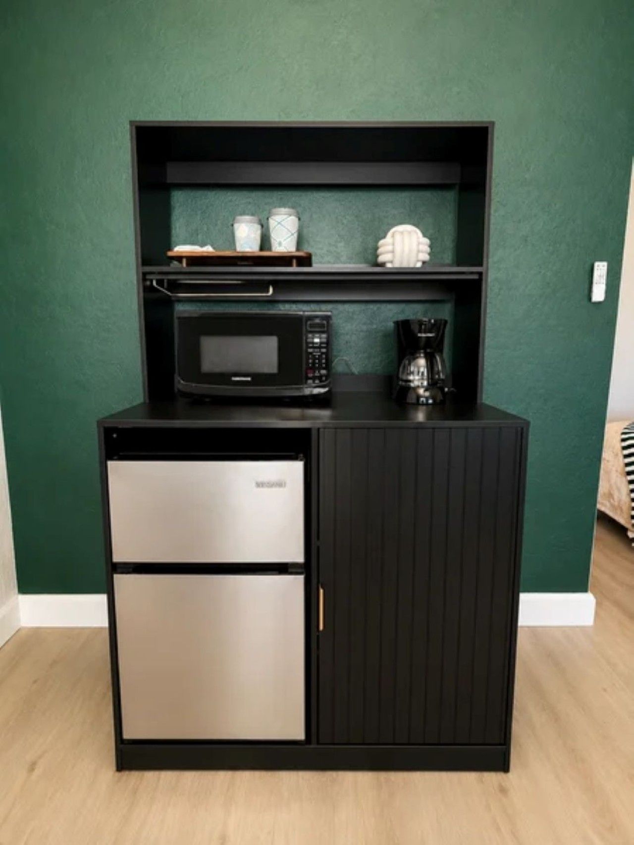 A kitchenette with a microwave, coffee maker, and two drawers.