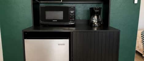 Una kitchenette equipada con microondas, cafetera y dos cajones.
