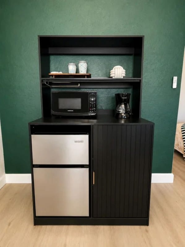 A kitchenette with a microwave, coffee maker, and two drawers.