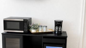A kitchenette with a microwave, coffee maker, and a small refrigerator.