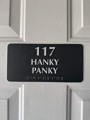 A house number sign with the number 117 and the name 'HANKY PANKY' on a white door.