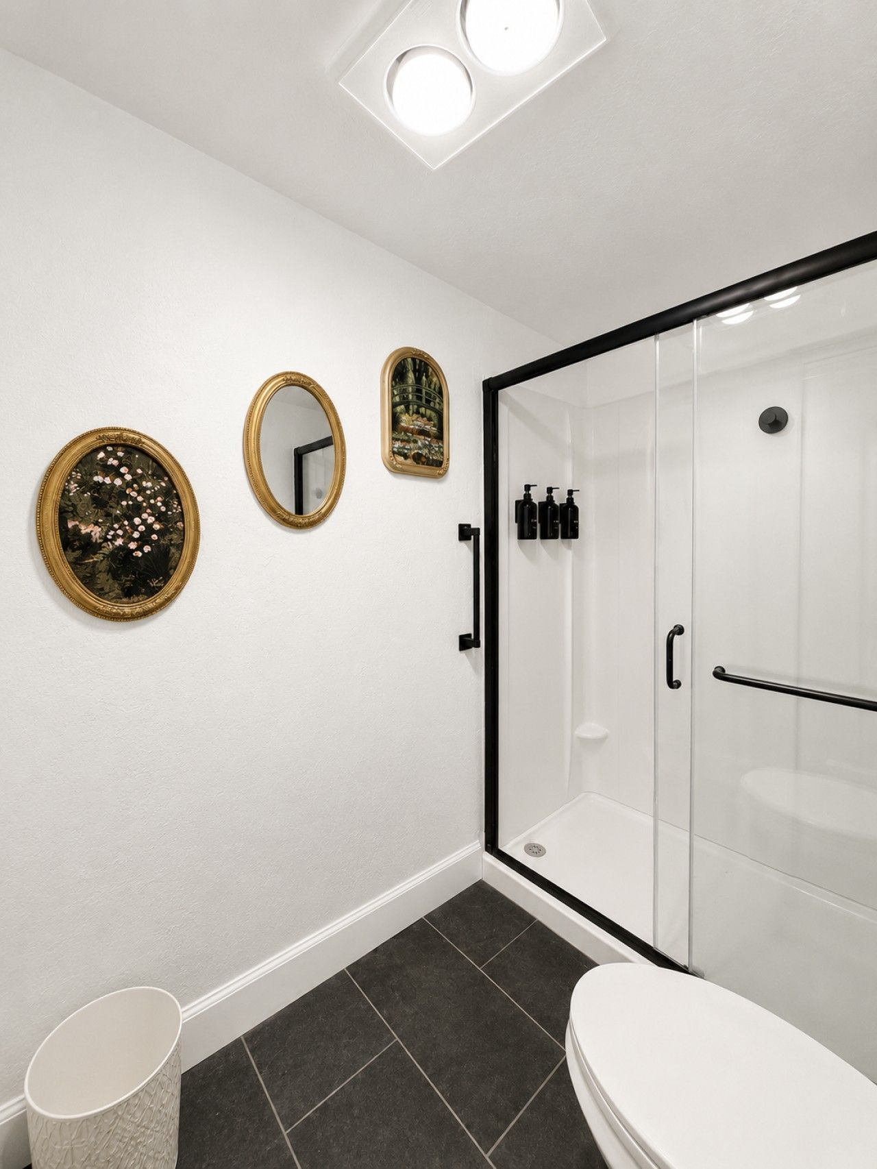 A modern bathroom with a glass shower enclosure, a toilet, and two wall-mounted mirrors.
