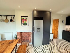 A modern kitchen with a built-in refrigerator, a brick fireplace, and a patterned floor. - Artistic house in Peaceful Kingswood (South Gloucestershire)