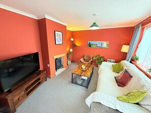 A living room with a flat-screen TV, a fireplace, a sofa, and a coffee table. - Artistic house in Peaceful Kingswood (South Gloucestershire)