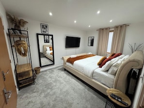 Une chambre à coucher avec un lit, une télévision, un miroir et une armoire.
