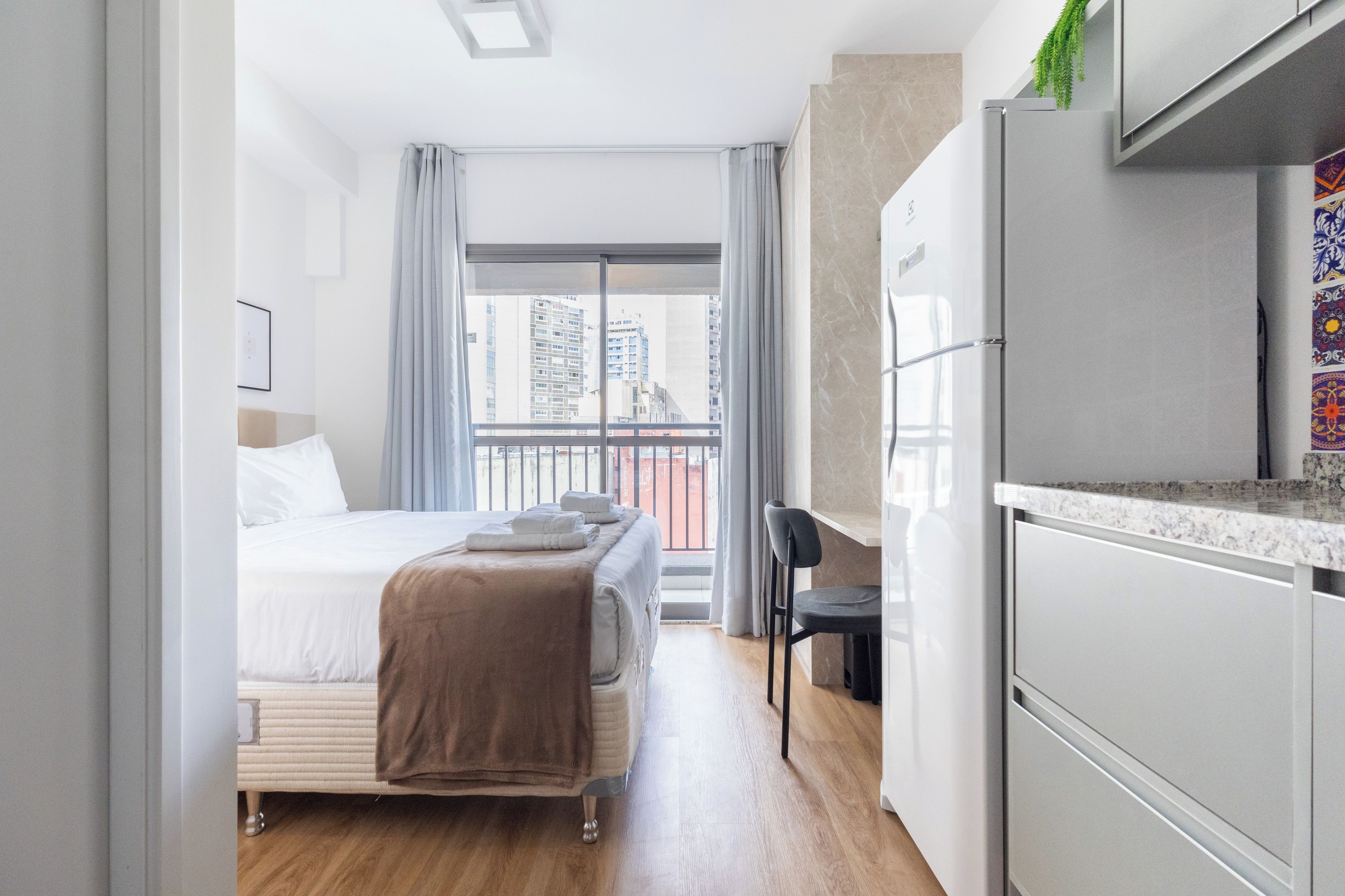 Una habitación de hotel moderna con cama, escritorio y kitchenette.