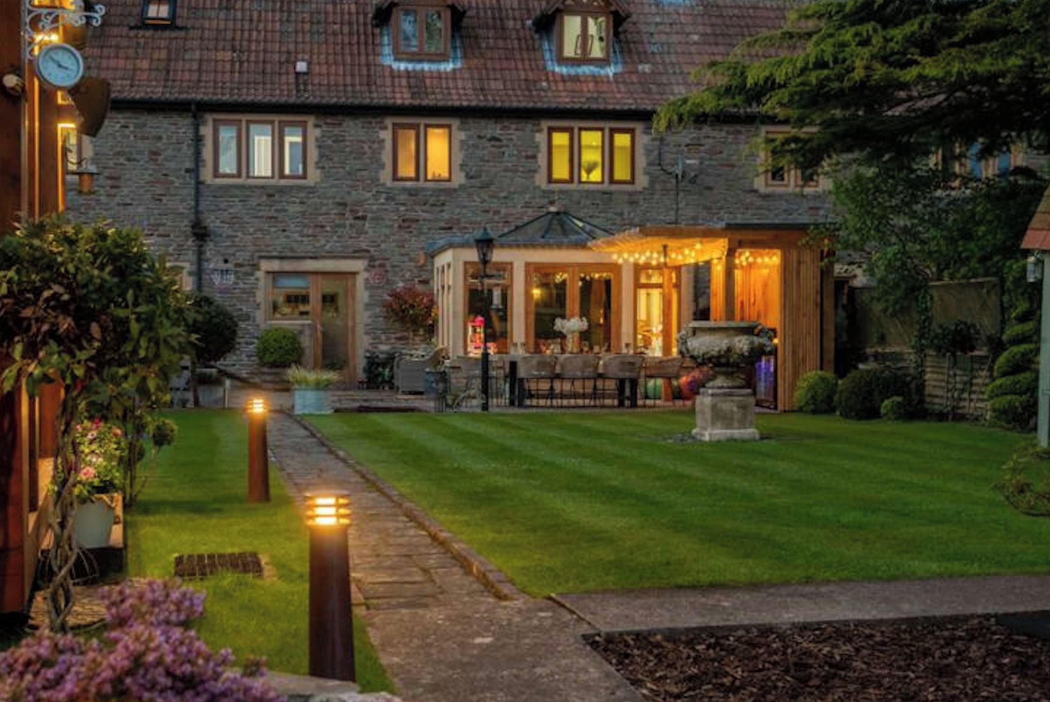 A stone building with a well-maintained lawn, a small outdoor seating area, and a pathway leading to the entrance.