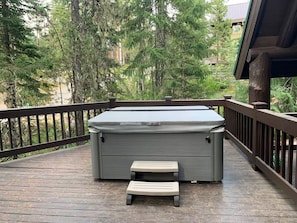 A deck with a hot tub, a small bench, and a wooden railing. - Government Camp Log Cabin | Walk to Town & Skibowl (Government Camp)