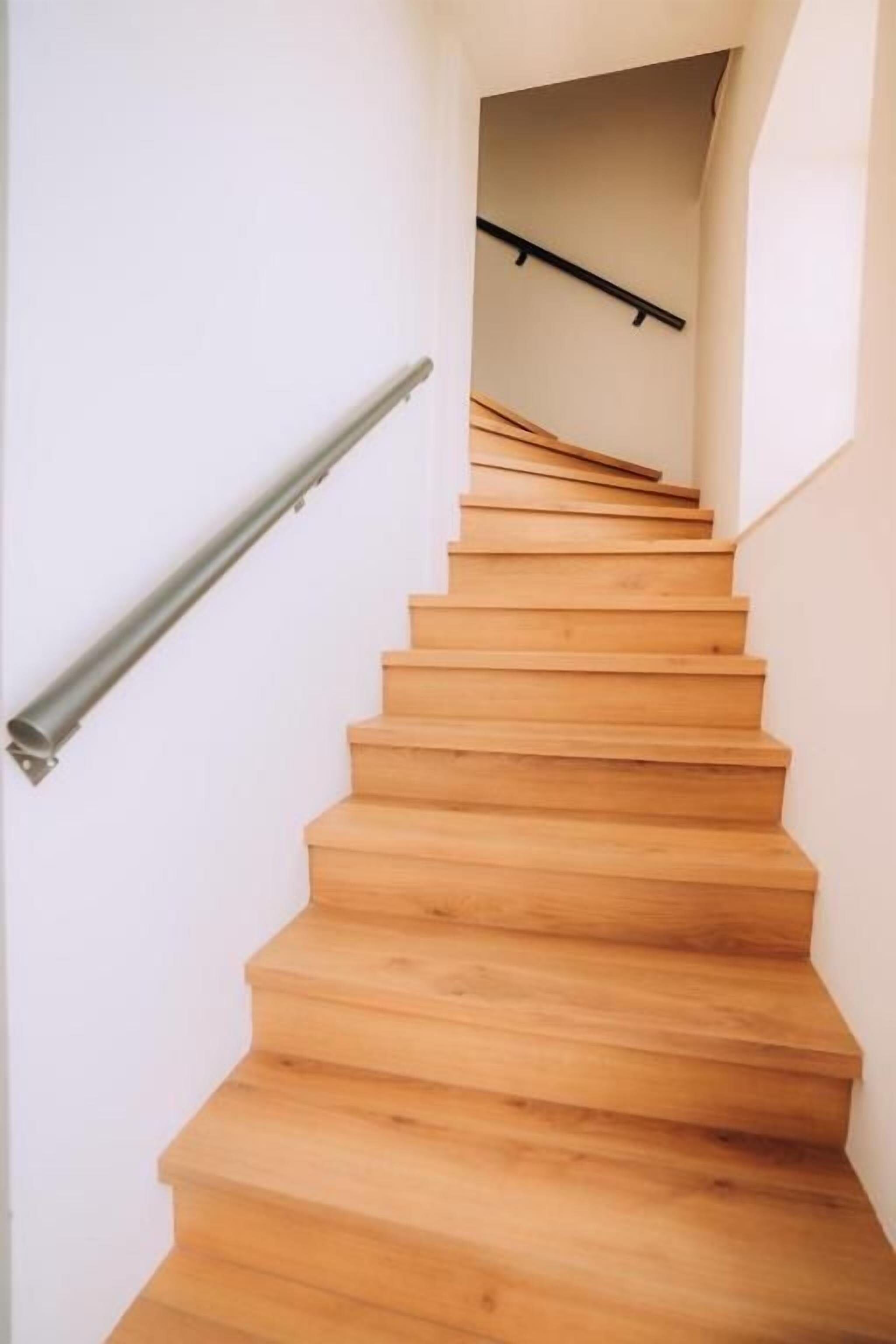 Una escalera de madera con barandilla de metal que conduce a un piso superior.