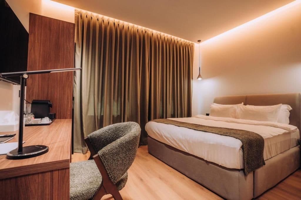 Una habitación de hotel con una cama, un escritorio, una silla y un espejo.