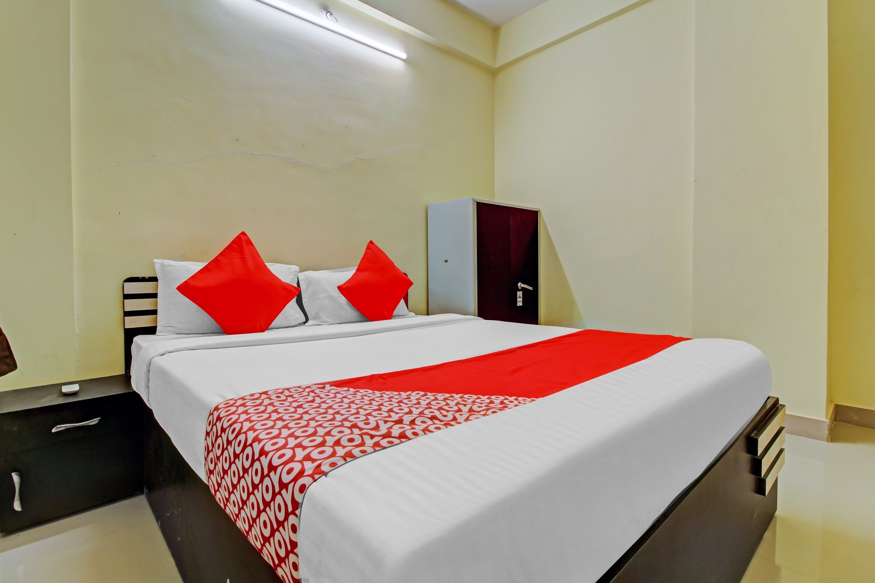 A hotel room with a bed, a nightstand, a wardrobe, and a desk.