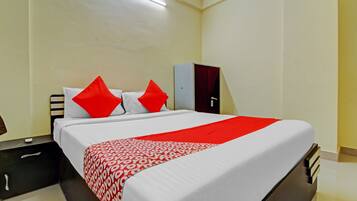 A hotel room with a bed, a nightstand, a wardrobe, and a desk.