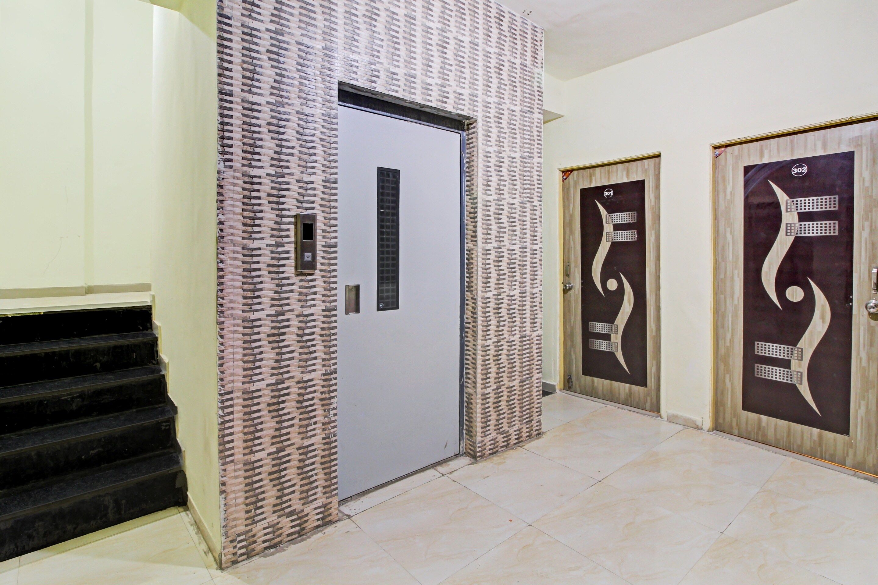A hallway with a staircase, a door with a modern design, and a wall with a patterned texture.