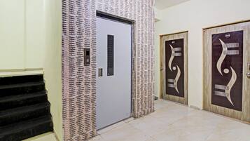 A hallway with a staircase, a door with a modern design, and a wall with a patterned texture.