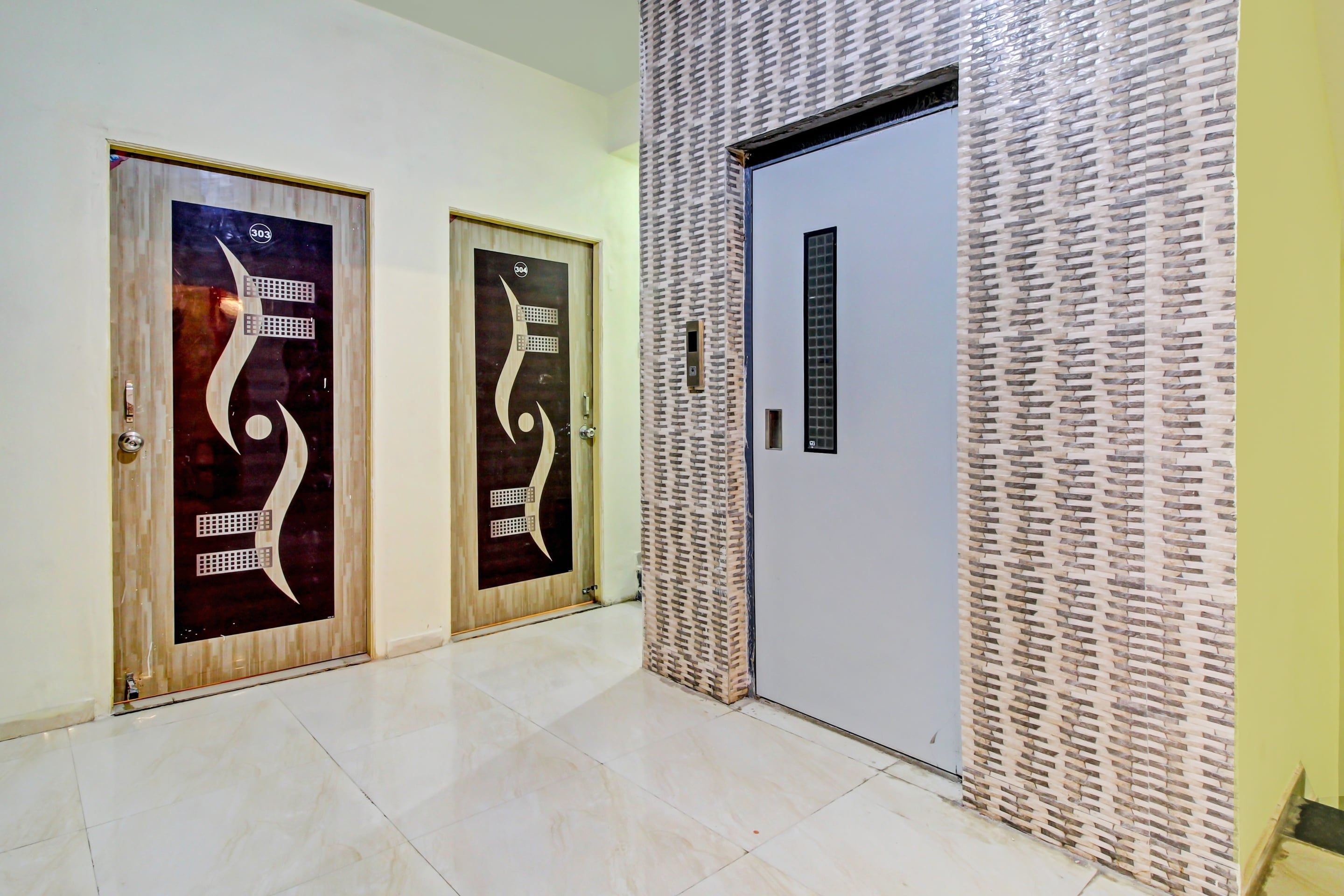 A hallway with two doors featuring abstract designs, a textured wall, and a plain door.