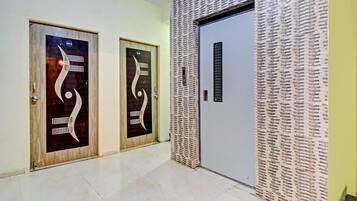 A hallway with two doors featuring abstract designs, a textured wall, and a plain door.