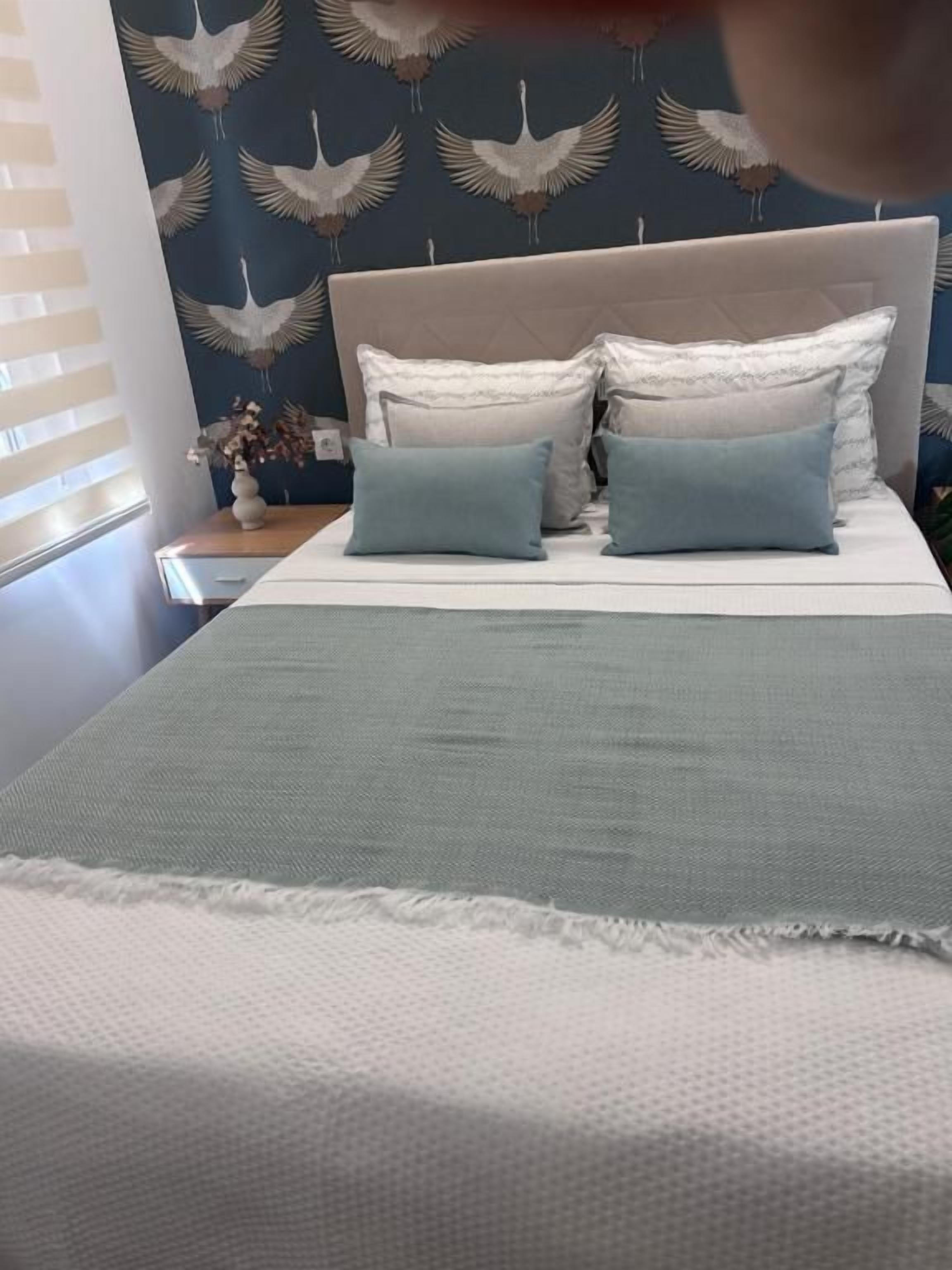 Una cama con cabecera, dos almohadas y una manta.
