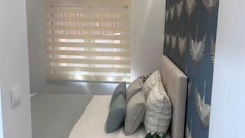 Una habitación pequeña y acogedora con cama, una mesita de noche con una planta y una ventana con persianas.