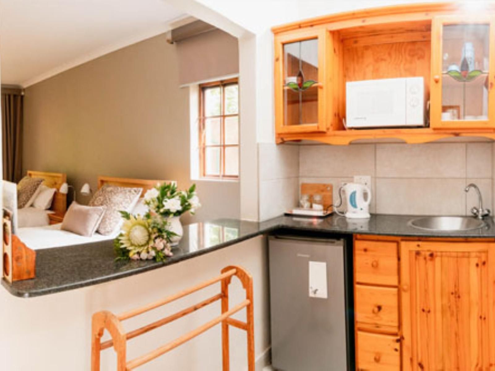 A hotel room with a bed, a small kitchenette, and a wooden cabinet with a mirror.