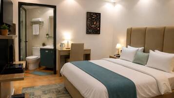 Una habitación de hotel con cama, escritorio, silla, televisor y baño.