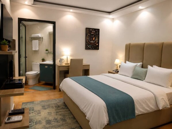 A hotel room with a bed, a desk, a chair, a television, and a bathroom.