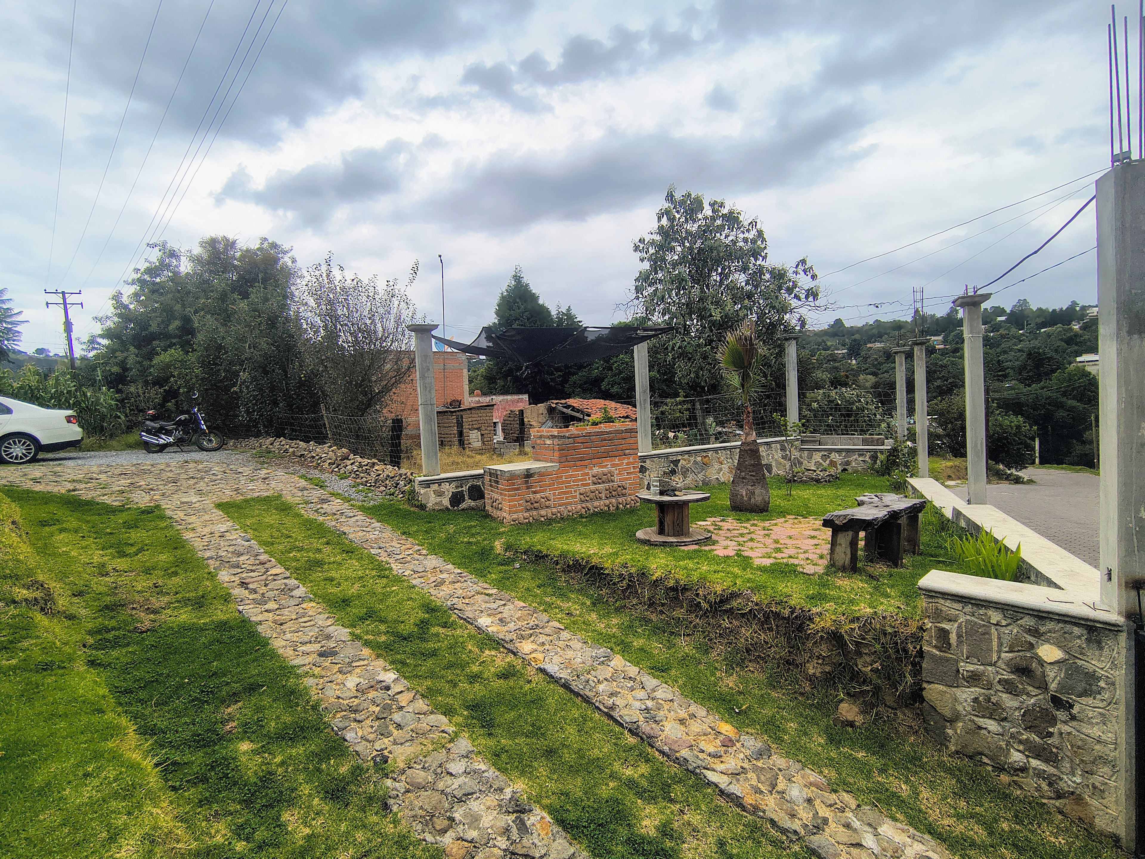 Un sendero pavimentado que conduce a una construcción de ladrillo con una pequeña mesa y una palmera.