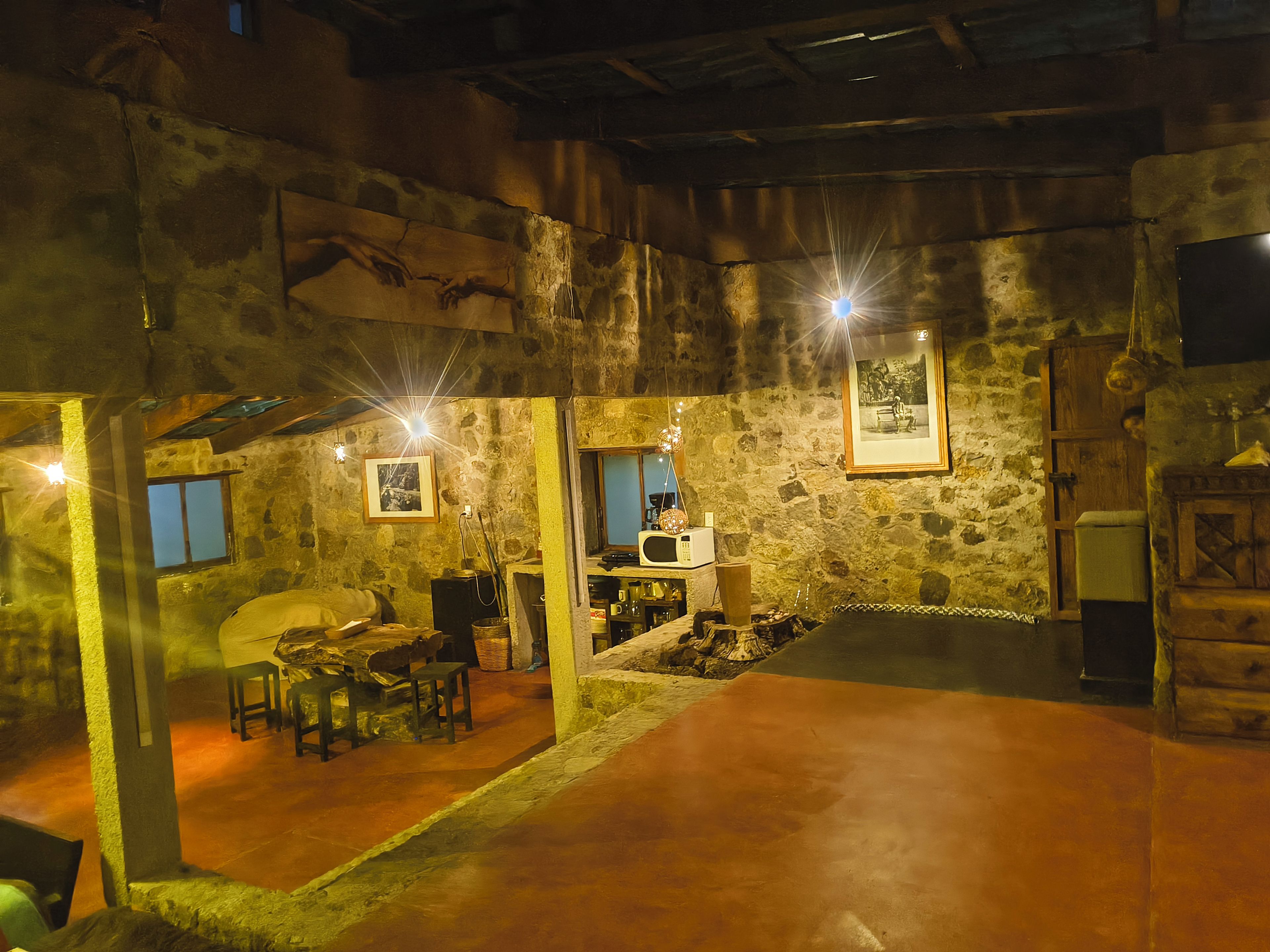 A rustic interior with stone walls, a dining area with a table and chairs, and a fireplace.