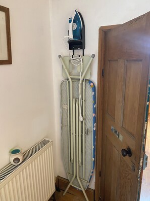 A corner room with a radiator, a door labeled 'Office', and an ironing board with an iron. - 1772 period detached cottage
In the heart of town with parking (Falmouth)