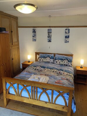 A bedroom with a wooden bed frame, a bedside table with a lamp, and a wardrobe. - 1772 period detached cottage
In the heart of town with parking (Falmouth)