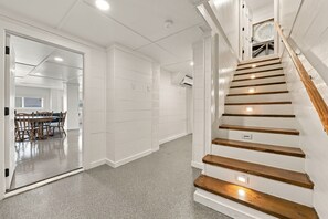 A staircase with wooden steps and white walls, leading to an upper floor. - Marsh Bend: 8  BR, 5  BA House in Pawleys Island, Sleeps 21 (Pawleys Island)