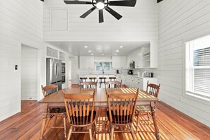 A spacious kitchen with white cabinets, a dining table with wooden chairs, and a ceiling fan. - Marsh Bend: 8  BR, 5  BA House in Pawleys Island, Sleeps 21 (Pawleys Island)