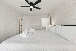 A hotel room with a large bed, a ceiling fan, and a view of the hallway. - Marsh Bend: 8  BR, 5  BA House in Pawleys Island, Sleeps 21 (Pawleys Island)