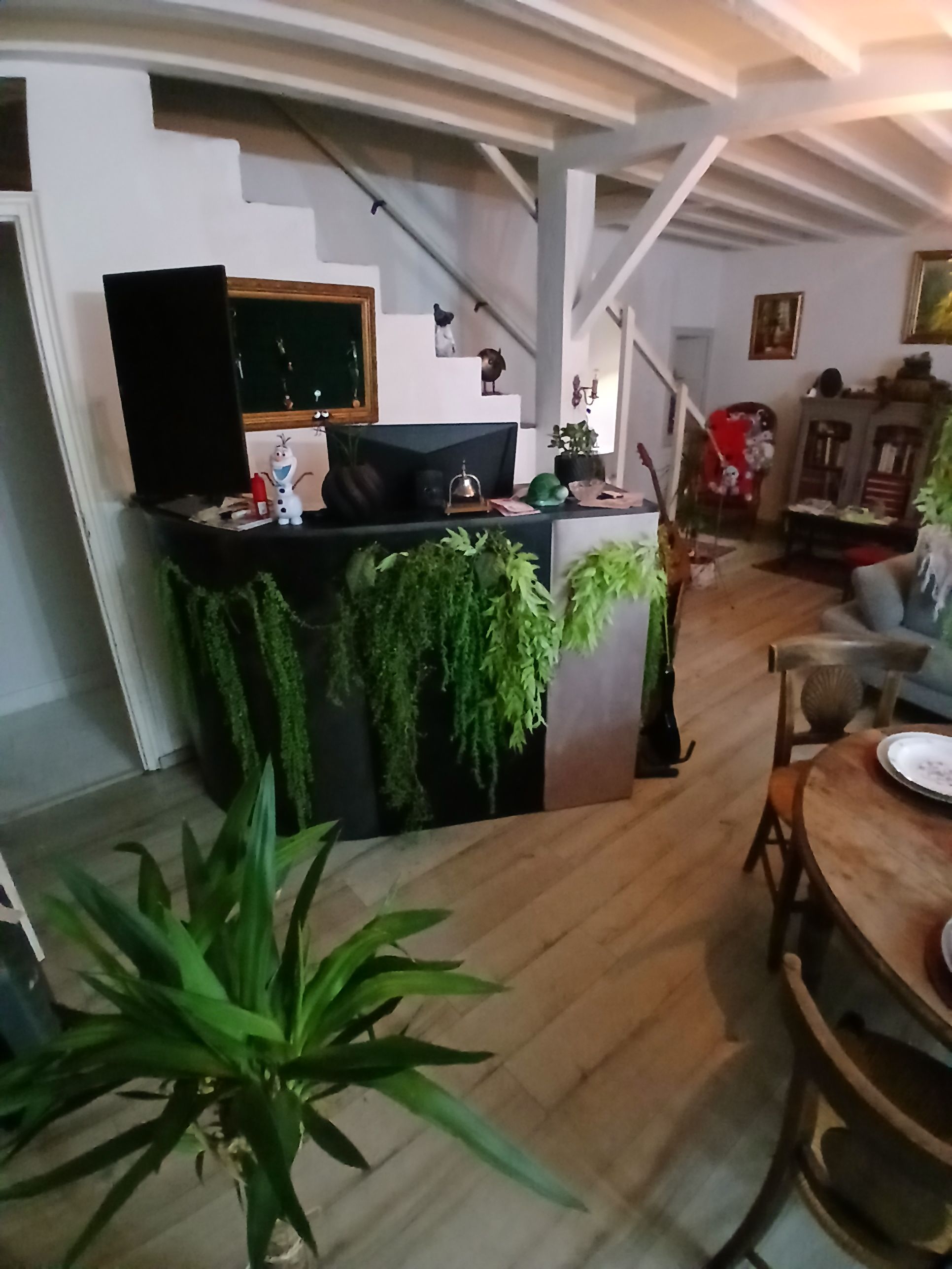 Una cucina moderna con un piano di lavoro nero, un piccolo frigorifero e un'area pranzo con tavolo e sedie in legno.