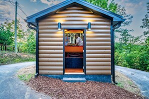 A log cabin with a small porch and a door leading to an interior with a fireplace. - Intimate Couples Oasis! Views! Movie Theater! Love (Pigeon Forge)