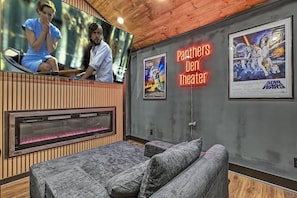 A room with a fireplace, a large flat-screen TV, a neon sign reading 'Panthers Den Theater,' and framed posters on the wall. - Intimate Couples Oasis! Views! Movie Theater! Love (Pigeon Forge)