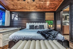 A modern bedroom with a large bed, a vanity, and a view of the outdoors. - Intimate Couples Oasis! Views! Movie Theater! Love (Pigeon Forge)