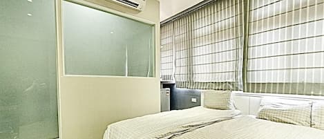 Une chambre à coucher avec un lit, une armoire et une fenêtre avec des rideaux.