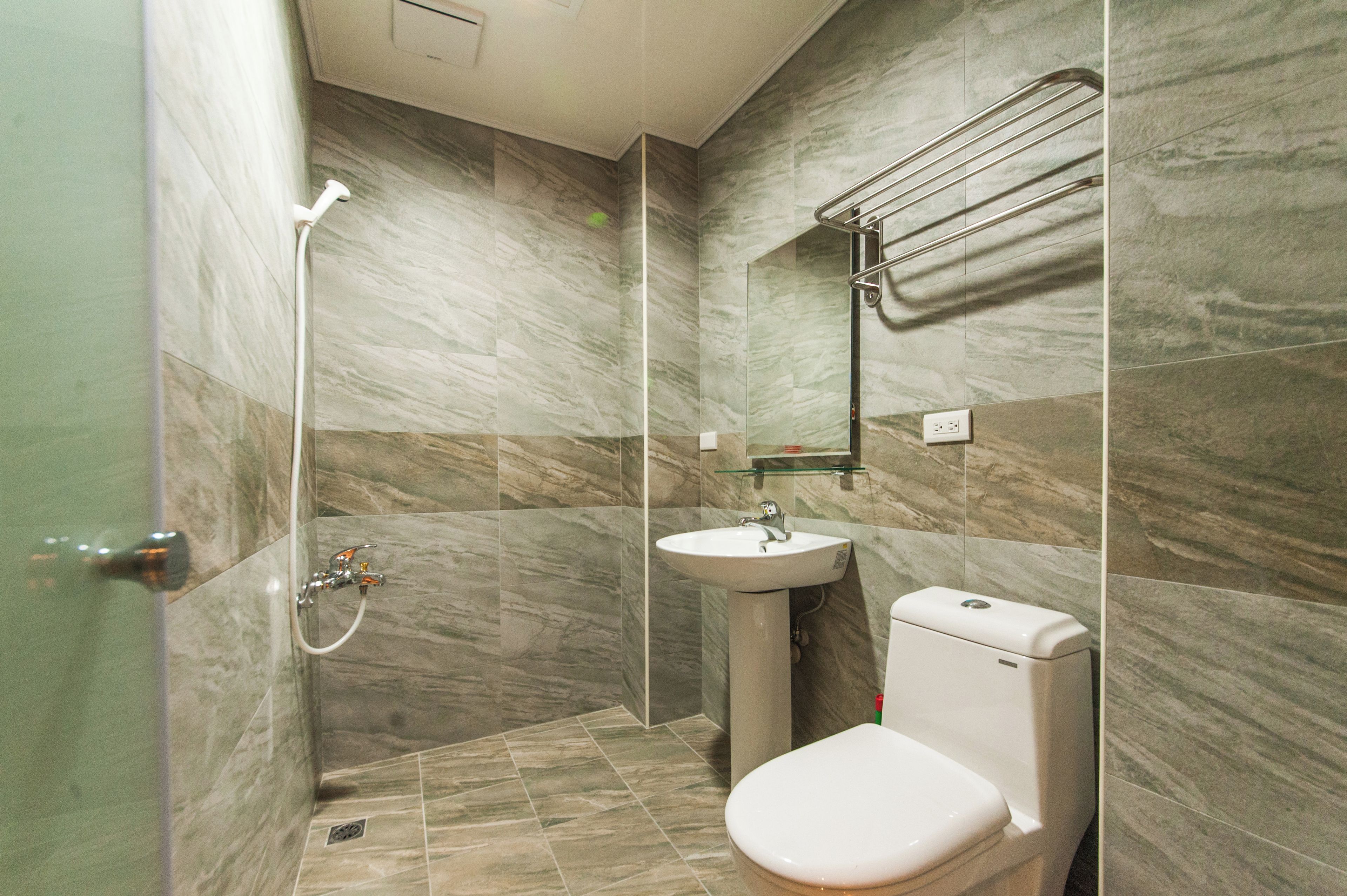 A bathroom with a shower, sink, toilet, and a glass shelf.