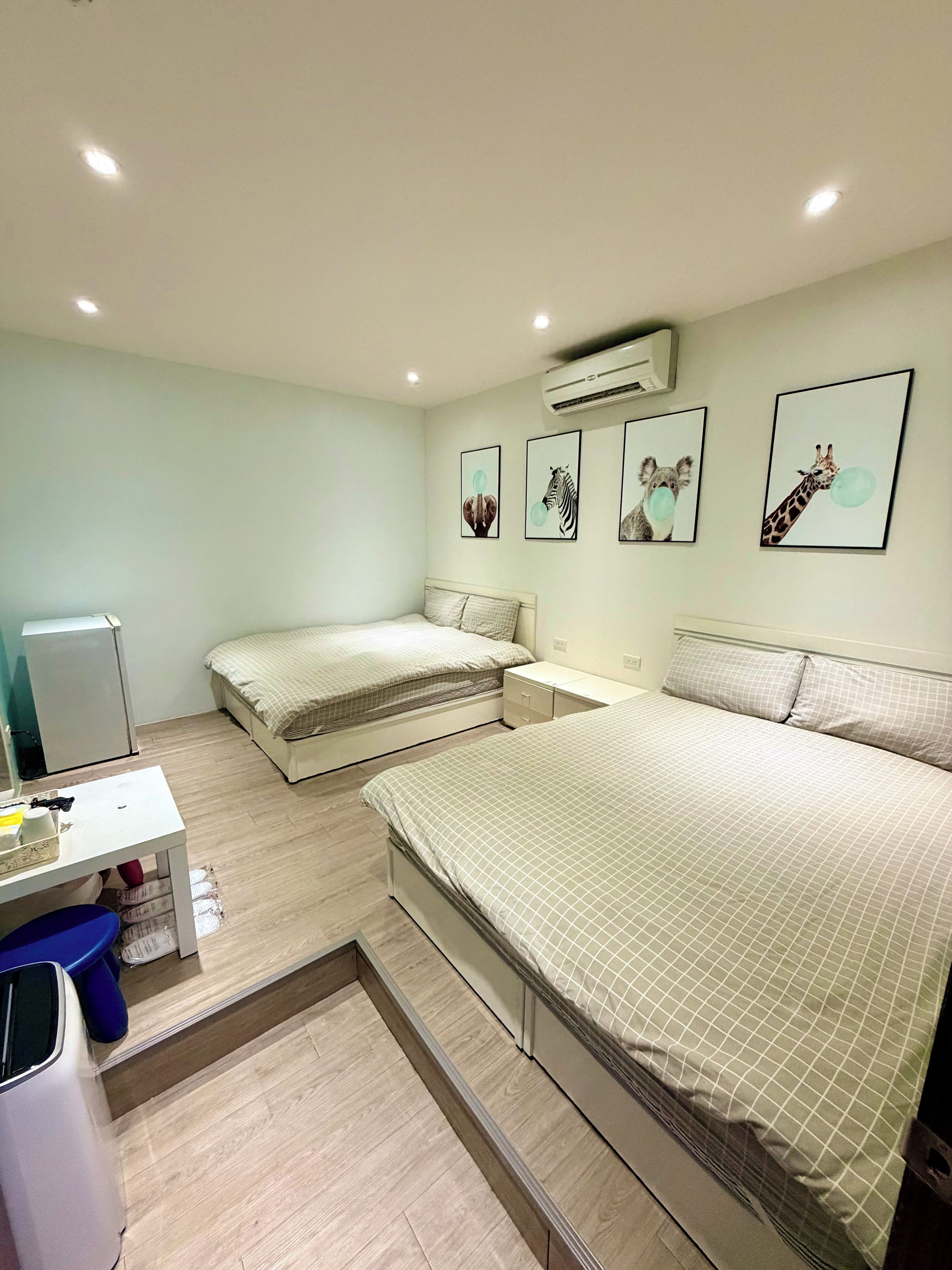 A bedroom with two beds, a desk, and an air conditioner.