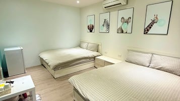A bedroom with two beds, a desk, and an air conditioner.