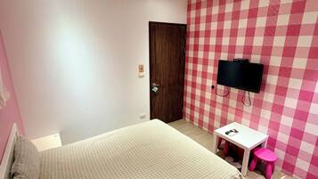 A bedroom with a bed, a desk, a chair, a television, and a door.