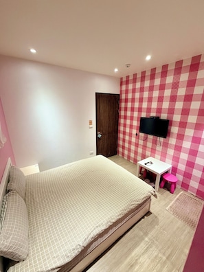 Un dormitorio con una cama, un escritorio, una silla, un televisor y una puerta.