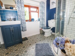 A bathroom with a toilet, shower, and patterned floor tiles. - Greig House Farm (Abergavenny)