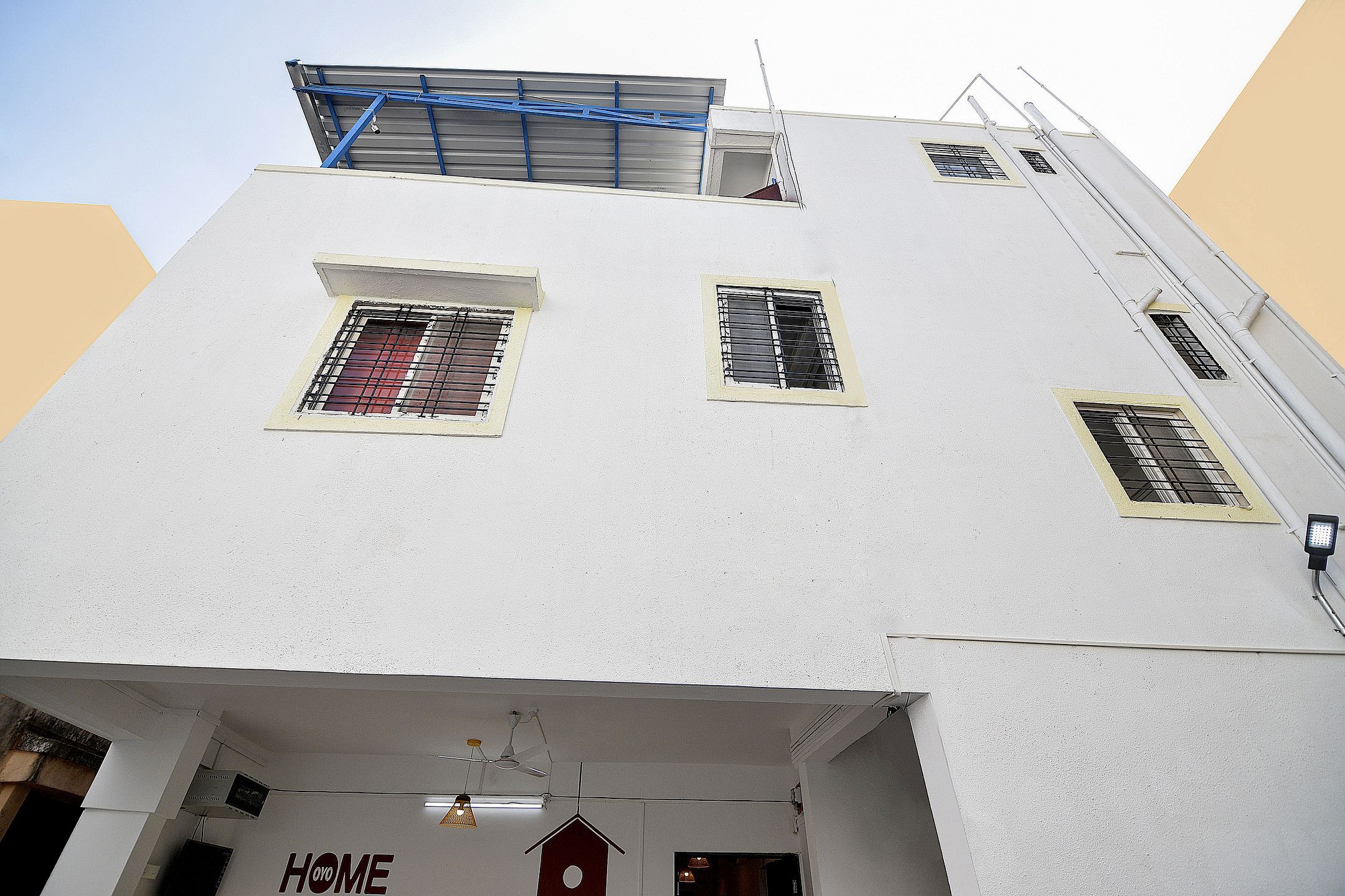 A white building with multiple windows, a visible roof, and a sign that reads 'HOME'.
