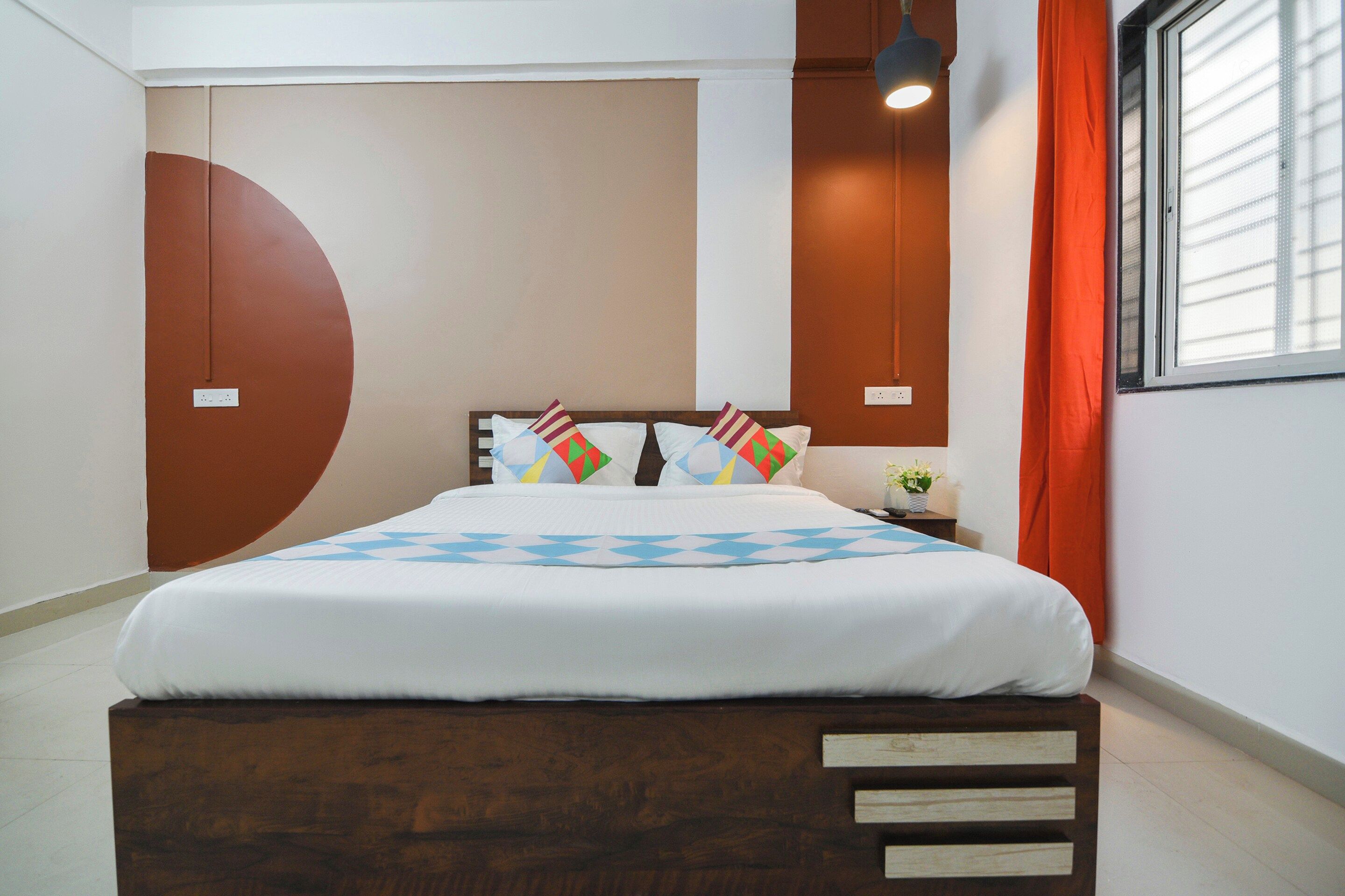 A neatly made bed with a geometric-patterned bedspread, a wooden headboard, and multiple pillows with colorful geometric patterns.