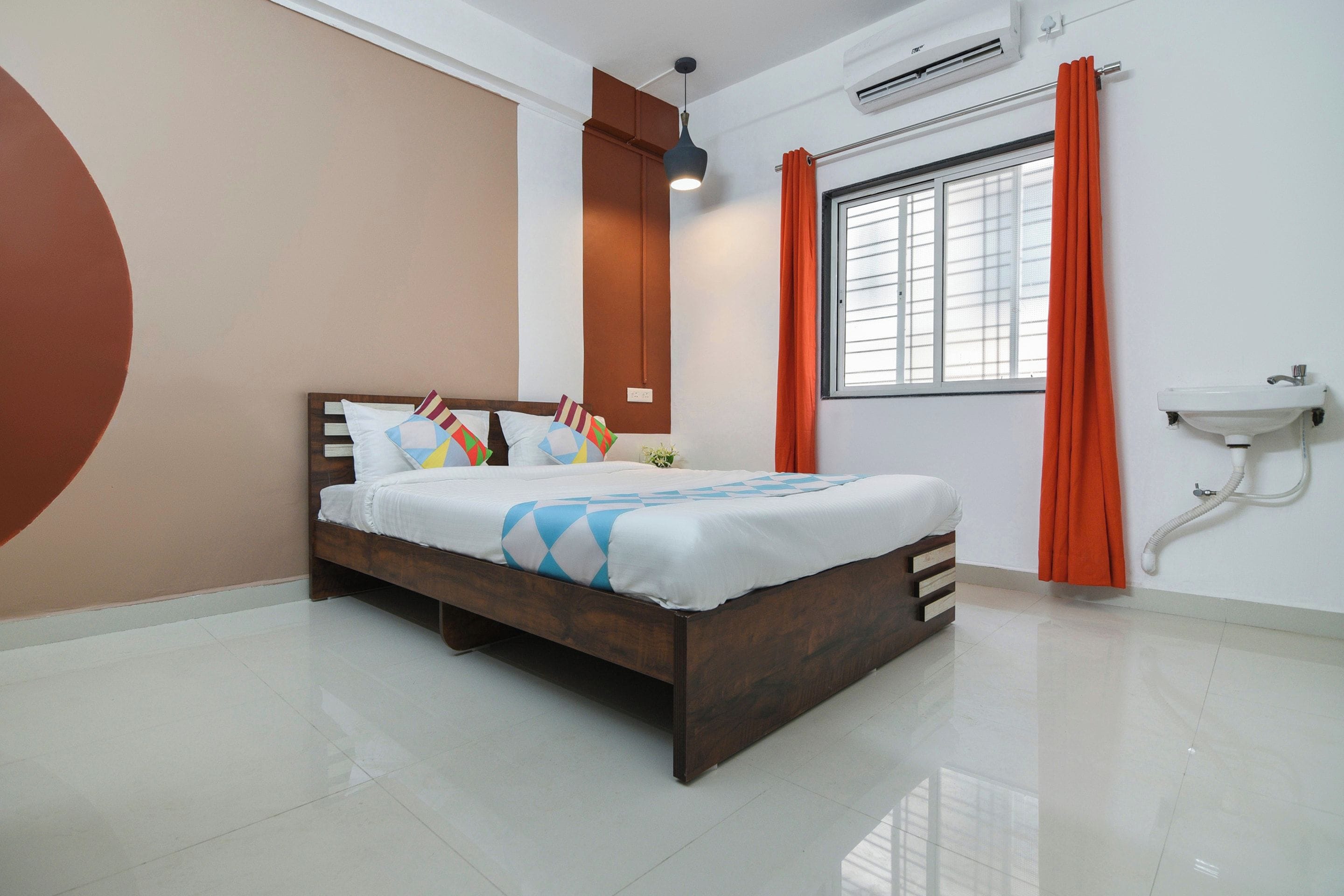 Un dormitorio moderno con una cama grande, una mesita de noche, una ventana con cortinas, un equipo de aire acondicionado y un lavamanos en la pared.
