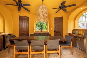 A dining area with a large wooden table, six chairs, and two ceiling fans. - Las Catalinas Luxury Villa Pool & Beach Club Access (Las Catalinas)