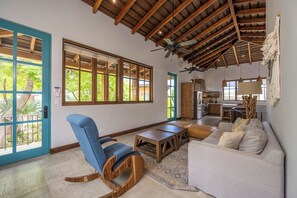 A spacious living area with a high ceiling, large windows, and a kitchen in the background. - Las Catalinas Luxury Villa Pool & Beach Club Access (Las Catalinas)